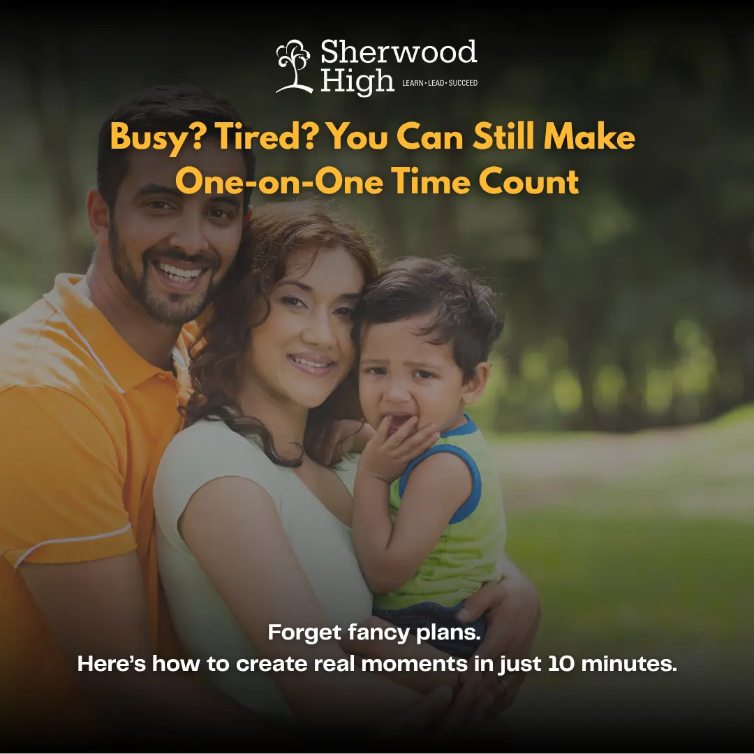 A smiling couple is holding their young child in an outdoor park-like setting. The child looks emotional while being comforted in the mother's arms. The father is standing beside them with a supportive expression